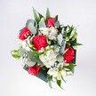 A hand-tied bouquet in rich reds, whites, and fresh greens rests as if just placed on a kitchen table in Collier Row, glowing softly in natural daylight. At its heart, velvety red roses open in full, layered spirals, their petals deep and luxurious, surrounded by ruffled pink-red carnations that add movement and texture. Clusters of snow-white daisies and small white chrysanthemums bring a clean, gentle brightness, their daisy-like faces echoing the easy cheer of a sunny morning walk through nearby Raphael Park. Threaded delicately between the larger blooms, tiny clouds of gypsophila - baby's breath - create a light, airy veil, softening every edge and catching the eye like scattered stars. Around the flowers, eucalyptus stems arc gracefully, their rounded, silvery-green leaves adding a cool, contemporary note, while deeper tropical foliage frames the bouquet, giving it structure and a sense of fullness without heaviness. The mix of textures invites the touch: the smooth rose petals, the frilled carnations, the crisp greenery with its faint herbal scent that suggests freshness and care. The design feels considered but relaxed, like something chosen to mark a happy milestone rather than a formal occasion - perfect for a birthday, a homecoming, or a quiet well done after a big achievement. One can almost imagine this bouquet being carried down Collier Row Lane for same-day delivery, bringing with it a sense of optimism, warmth, and the comforting presence of fresh flowers arranged with genuine local expertise.